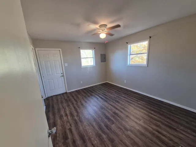 a view of an empty room with wooden floor and a window