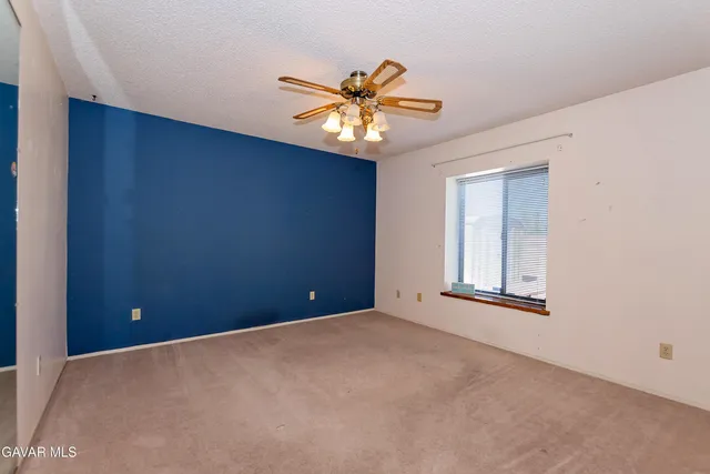 an empty room with a window and a fan