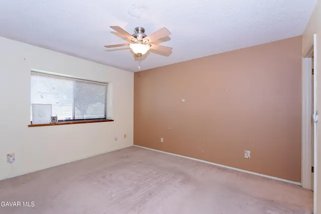 an empty room with a ceiling fan and a window