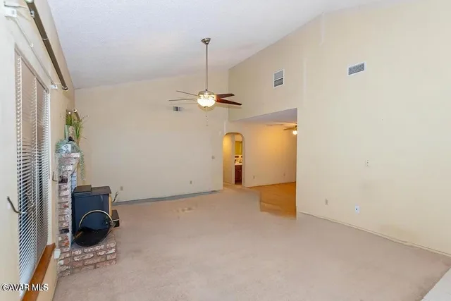 a view of an empty room with a window and a kitchen