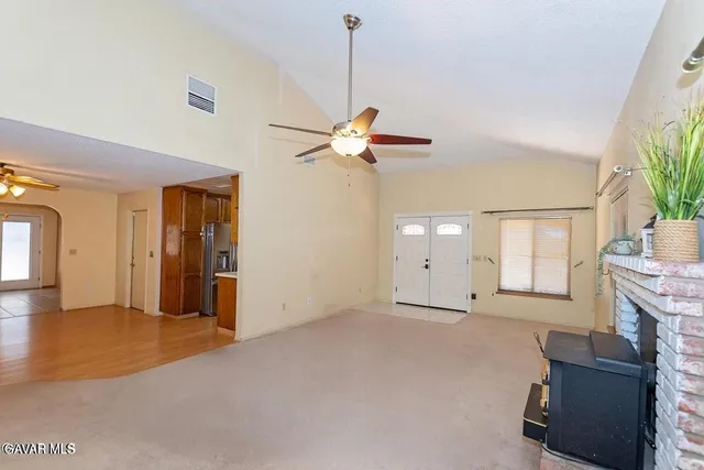 a view of an empty room with chandelier fan and a window