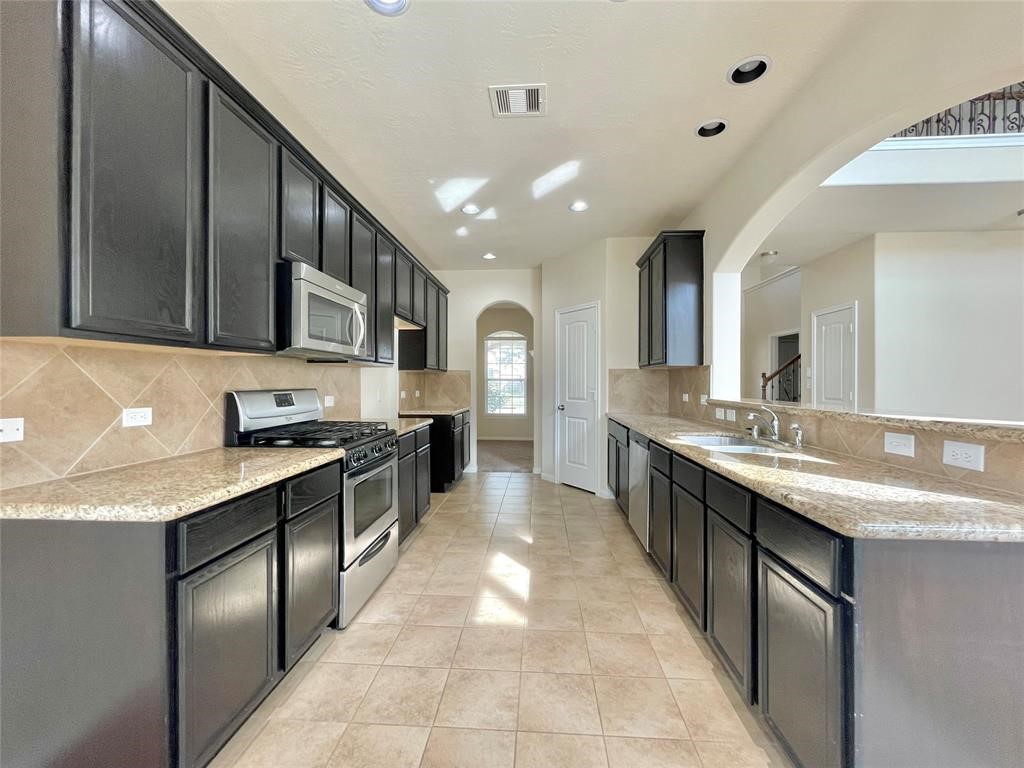 25015 Diamond Ranch Drive Katy, TX 77494 - Photo 8 of 27 a large kitchen with stainless steel appliances kitchen island granite countertop a sink and cabinets