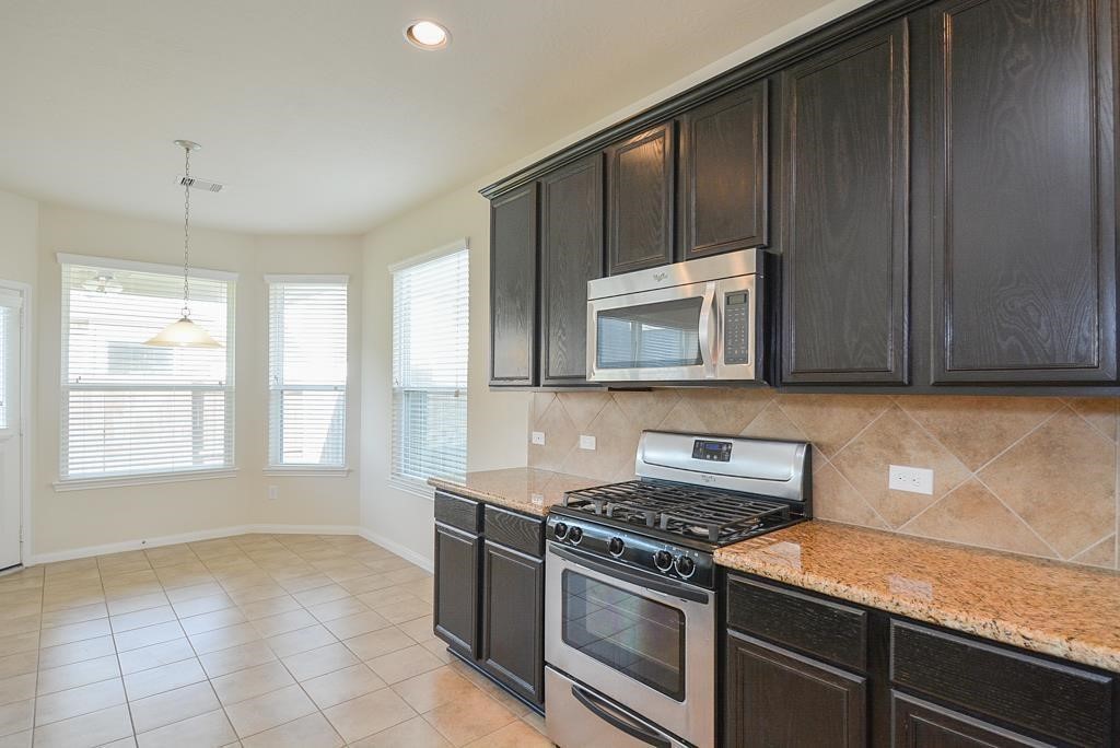 25015 Diamond Ranch Drive Katy, TX 77494 - Photo 10 of 27 a kitchen with granite countertop a stove a sink and a microwave