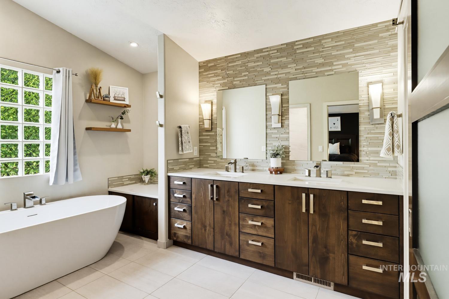 369 South Winthrop Way Boise, ID 83709 - Photo 28 of 50 Freestanding soaking tub with chrome fixtures, glass block window, double vanity with wood-finish cabinetry, quartz countertops, and a tiled accent wall