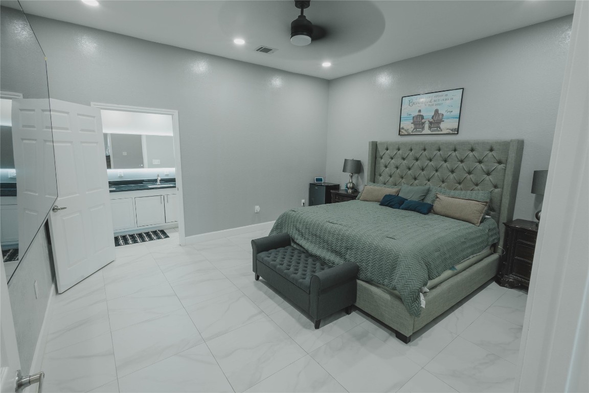 918 Fresa Road Pasadena, TX 77502 - Photo 11 of 47 Modern Primary Bedroom with a large bed, elegant headboard, and neutral décor. The room features high ceilings, recessed lighting, and an attached bathroom with a sleek vanity.