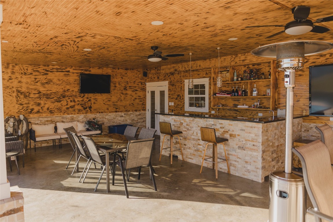 918 Fresa Road Pasadena, TX 77502 - Photo 21 of 47 A stylish outdoor entertainment area featuring a bar with stone accents, and ceiling fans. It's ideal for gatherings and relaxation.