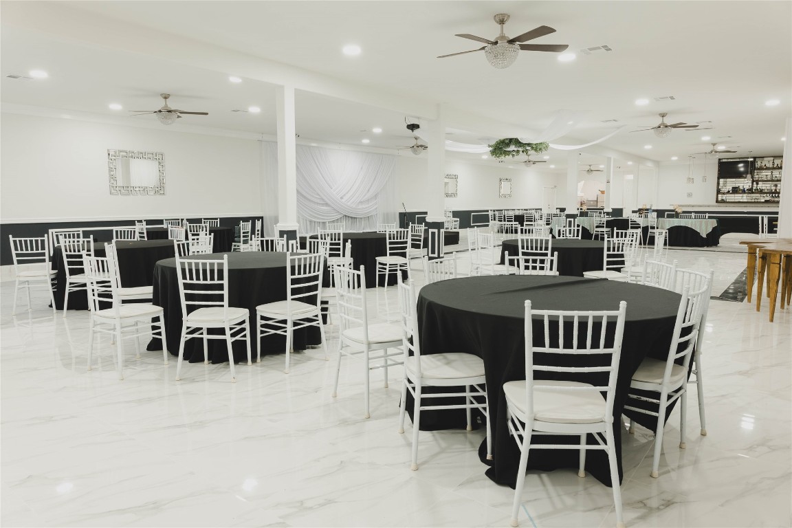 918 Fresa Road Pasadena, TX 77502 - Photo 30 of 47 And Idea how this Spacious event venue will look with elegant decor, featuring marble flooring, round tables with black tablecloths, white chairs, and ceiling fans. Perfect for hosting large gatherings or celebrations.