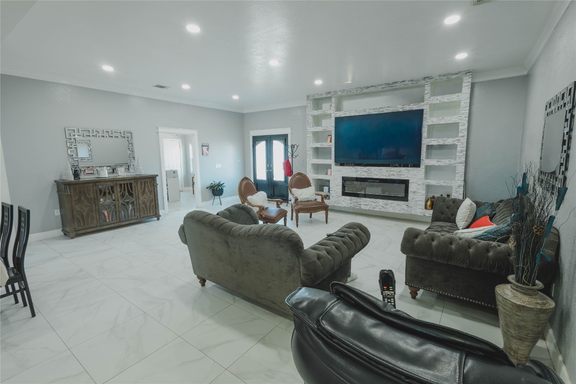 918 Fresa Road Pasadena, TX 77502 - Photo 6 of 47 Spacious living room with modern finishes, featuring a large built-in entertainment center, sleek tiled floors, and plush seating. Bright with ample lighting and elegant decor accents.