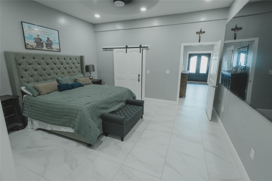 918 Fresa Road Pasadena, TX 77502 - Photo 10 of 47 Primary bedroom with a large, sleek tile flooring, and a barn-style sliding door.