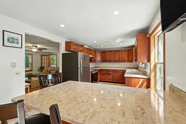 a kitchen with stainless steel appliances kitchen island granite countertop a refrigerator and a sink