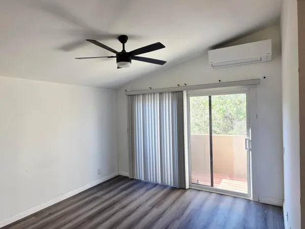 a view of empty room with wooden floor and fan