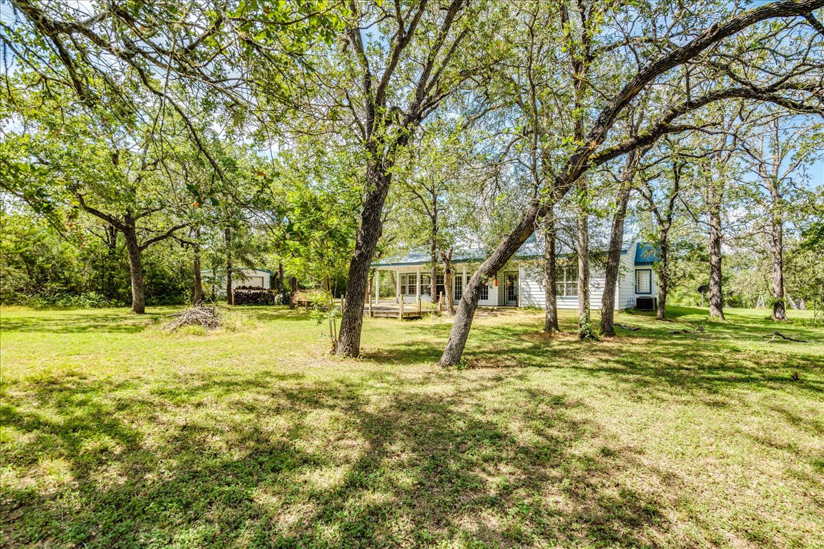 19106 Eyerley Road Manor, TX 78653 - Photo 30 of 40 A tranquil haven nestled amongst mature trees, this property offers serene country living with a charming house peeking through the foliage.