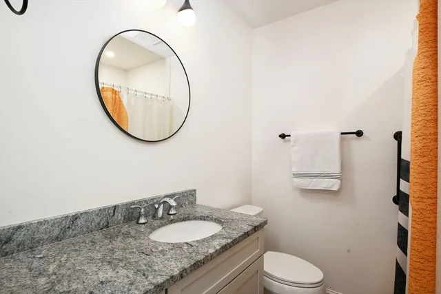 a bathroom with a granite countertop toilet a sink and a mirror