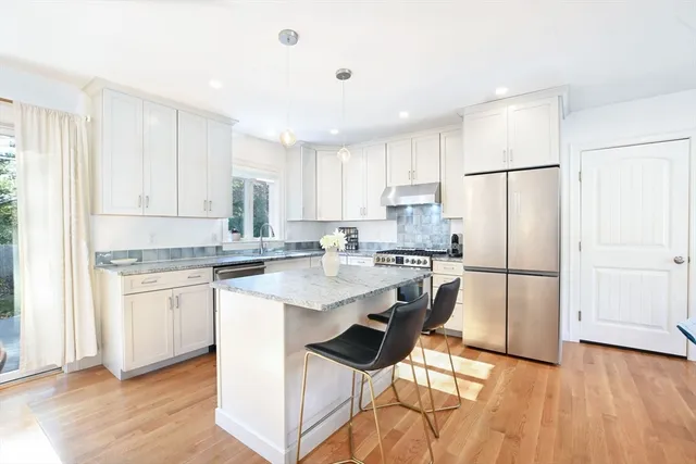 a kitchen with stainless steel appliances granite countertop a refrigerator a sink a stove a dining table and chairs