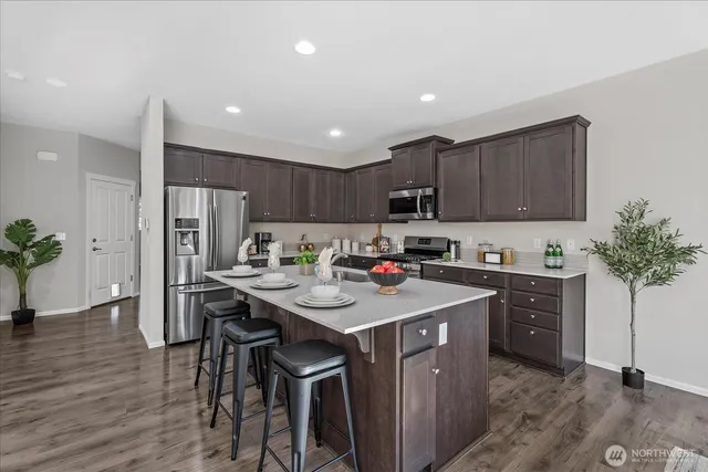 a kitchen with stainless steel appliances granite countertop a table chairs sink refrigerator and cabinets