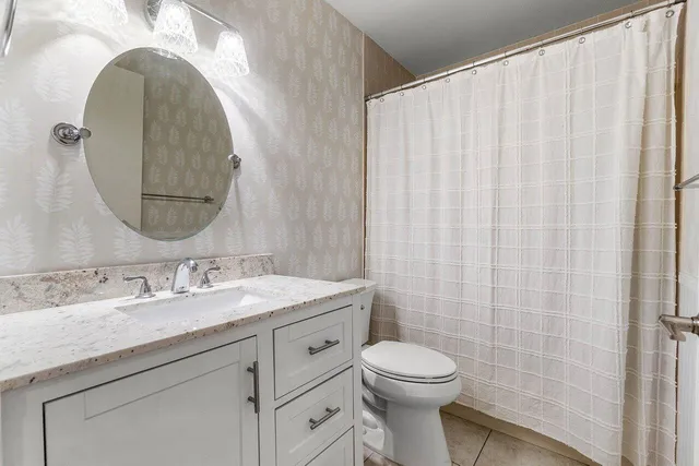 a bathroom with a granite countertop bathtub sink vanity mirror and toilet