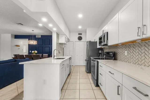 a kitchen with white cabinets and appliances