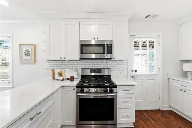 a kitchen with cabinets stainless steel appliances and a wooden floor