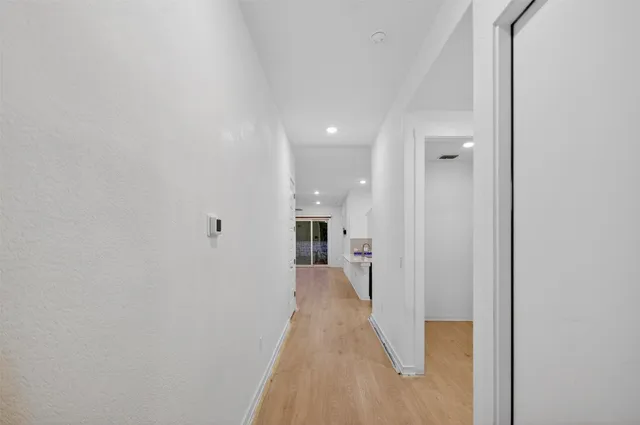 a view of a hallway with a wooden floor and a bathroom