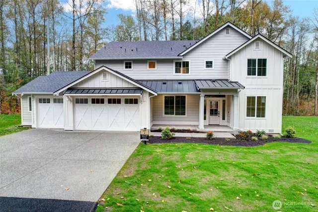 a view of a yard in front of a house with plants and large tree