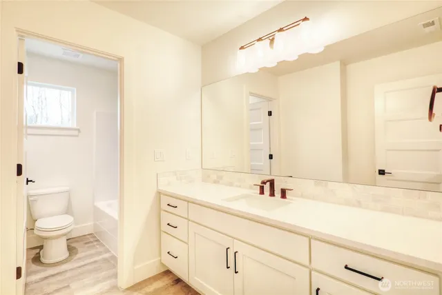 a bathroom with a granite countertop sink a toilet and a mirror