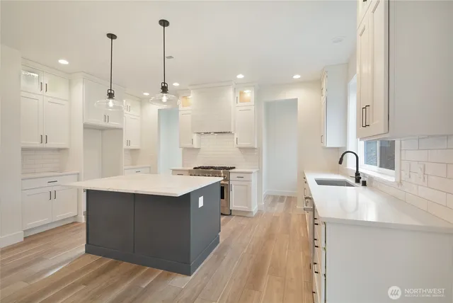 a large kitchen with kitchen island a sink a stove and a wooden floors