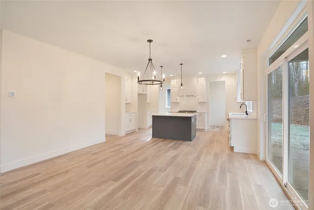 a view of a kitchen with kitchen island a sink wooden floor and a refrigerator
