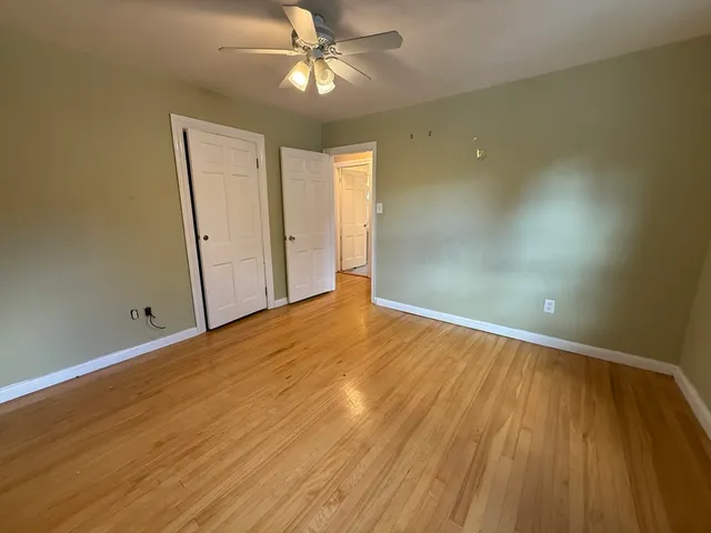 an empty room with wooden floor closet and windows