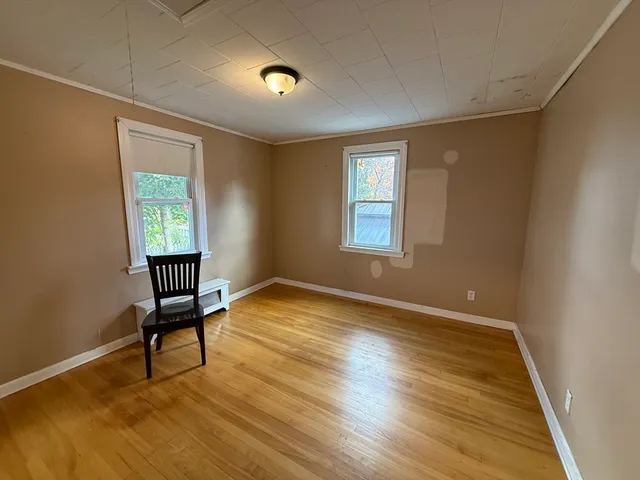 a view of an empty room with window and wooden floor