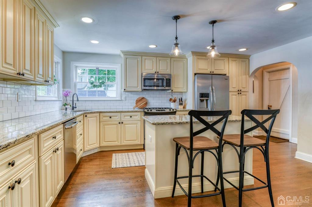 87 Chestnut Street Milltown, NJ 08850 - Photo 7 of 51 a kitchen with stainless steel appliances granite countertop a kitchen island a stove a table and chairs in it