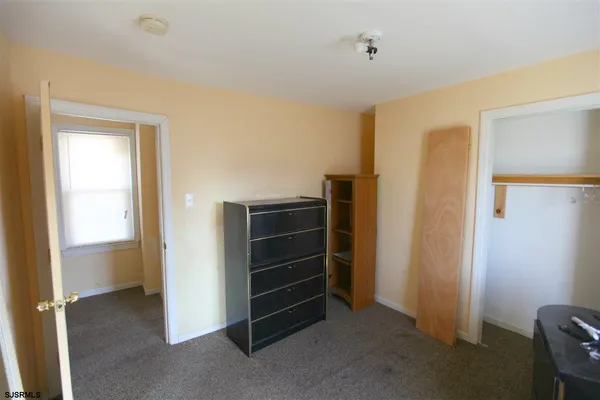 a view of an empty room with closet and a window