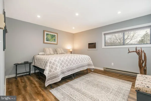 a bedroom with a bed and a dresser with wooden floor