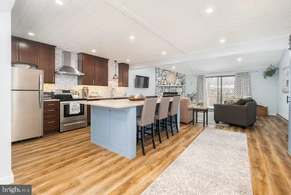 a large kitchen with stainless steel appliances granite countertop a stove oven a refrigerator a sink and a dining table with wooden floor