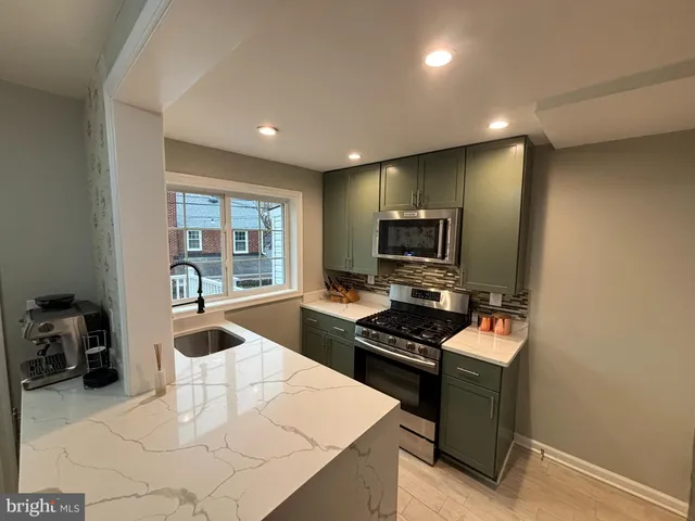 a kitchen with stainless steel appliances a stove top oven a sink a counter top space and cabinets