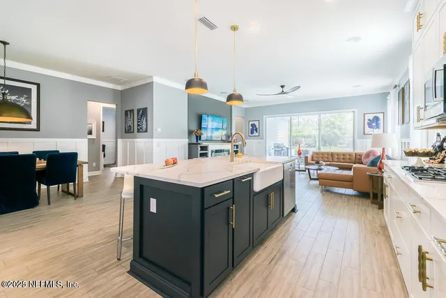 a large kitchen with stainless steel appliances granite countertop a stove a sink dishwasher and a refrigerator with wooden floor