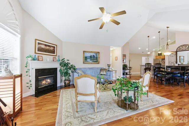 a view of a white house next to a yard with big trees