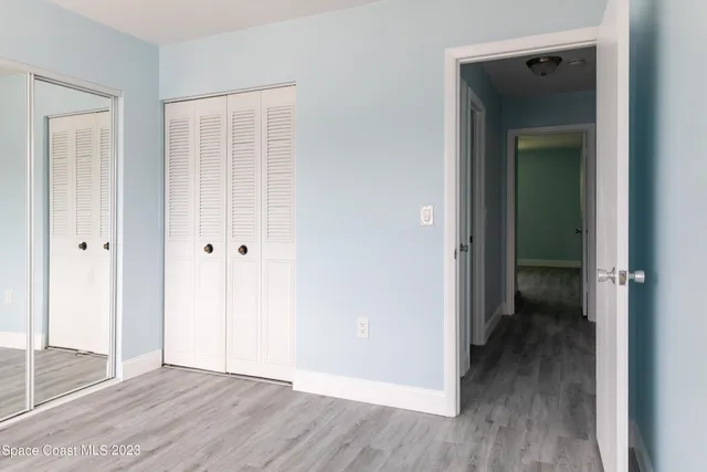 a view of an empty room with wooden floor and closet