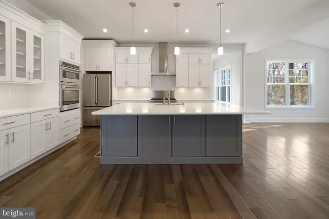 a kitchen with stainless steel appliances granite countertop hardwood floor sink stove and wooden cabinets