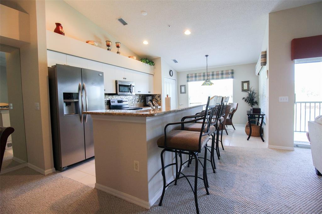 5301 Mahogany Run Avenue, Unit 1023 Sarasota, FL 34241 - Photo 35 of 56 a kitchen with stainless steel appliances kitchen island granite countertop a dining table chairs and a refrigerator