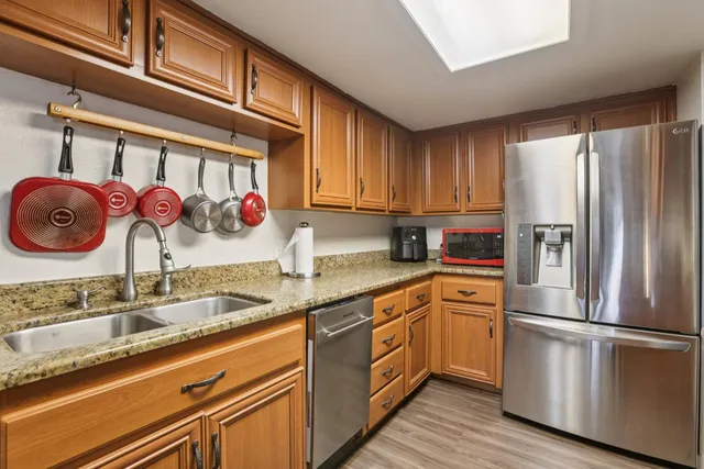 a kitchen with stainless steel appliances granite countertop a sink refrigerator and cabinets