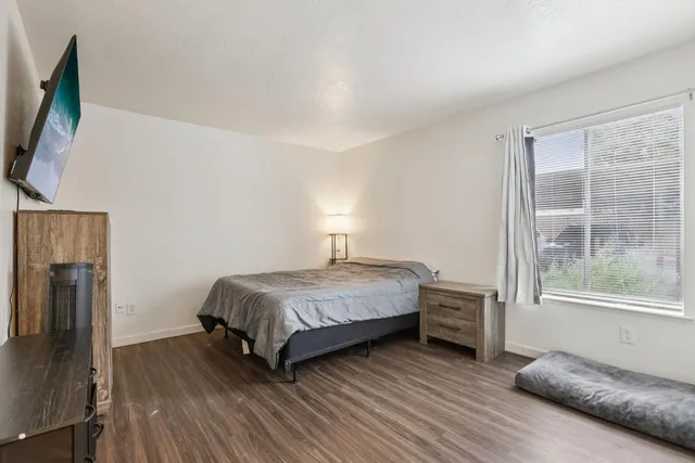 a bedroom with a bed flat screen tv and a large window