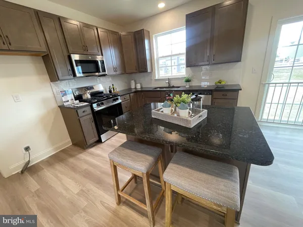 a view of kitchen with stainless steel appliances granite countertop a dining table and chairs