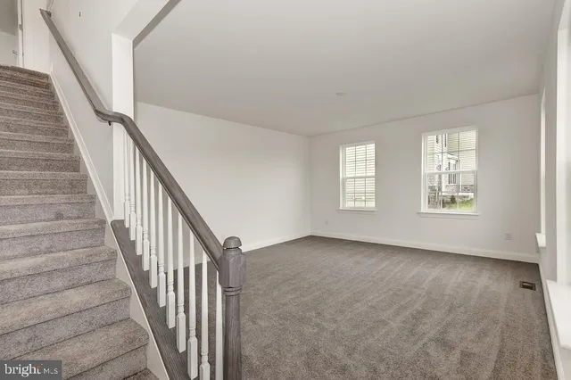 a view of an empty room with wooden floor and stairs