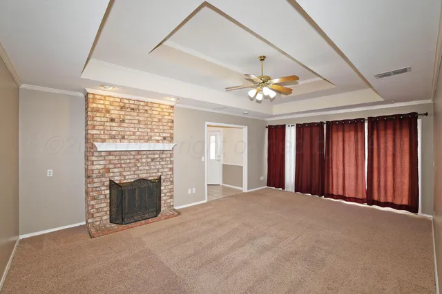 an empty room with windows fireplace and a ceiling fan