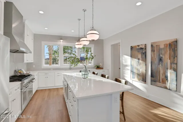 a kitchen with stainless steel appliances granite countertop a stove a refrigerator a oven a sink a dining table and chairs with wooden floor