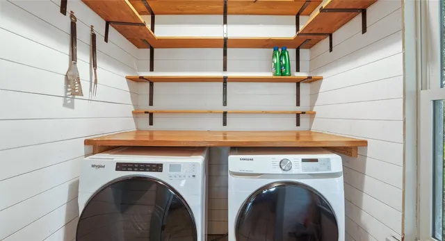 a view of washer and dryer with bathroom in the background