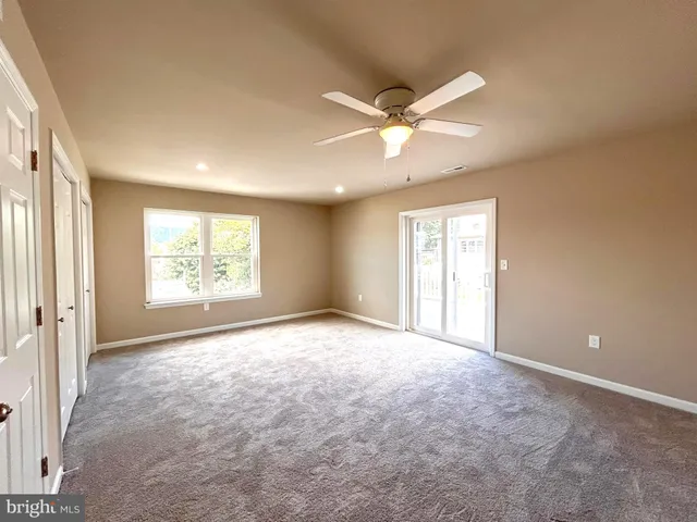 an empty room with windows and fan