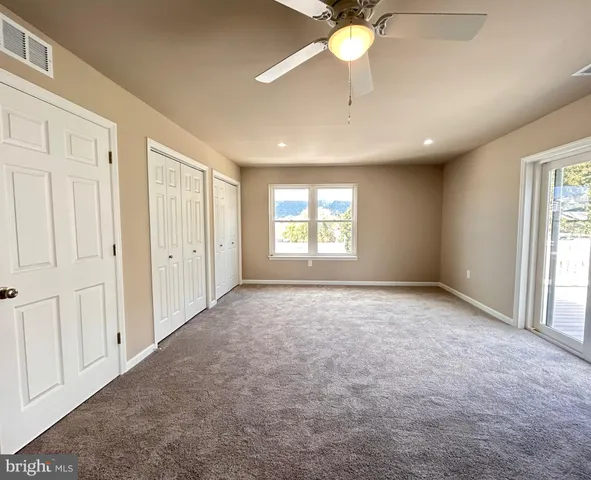 an empty room with windows and fan