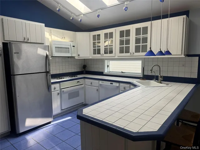 a kitchen with a refrigerator a sink and white cabinets