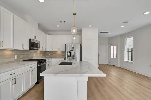 a kitchen with kitchen island a white counter top space stainless steel appliances and cabinets